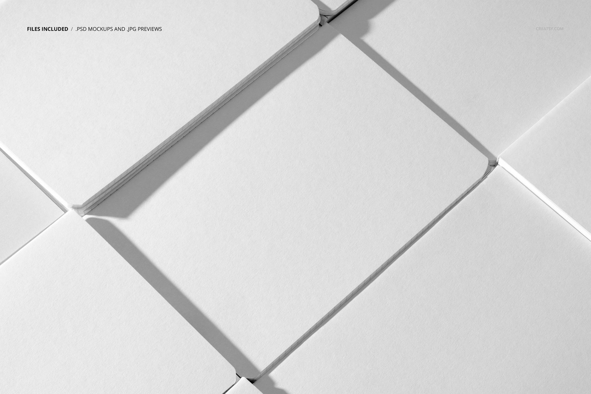 Stationery mockup featuring multiple white notebooks in an overlapping arrangement, viewed from a diagonal angle.
