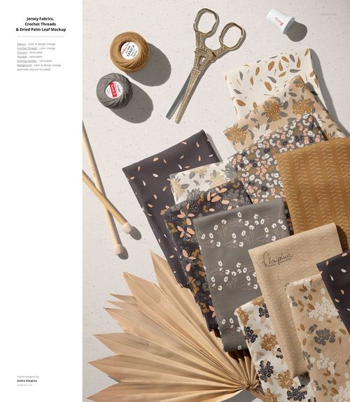 PSD mockup featuring layered jersey fabric swatches with botanical prints, sewing accessories, and natural textures.