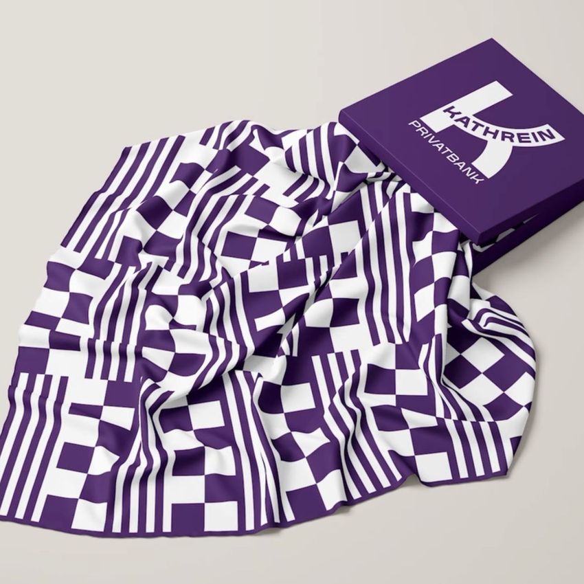 Twill silk scarf mockup featuring a purple and white geometric pattern, draped on a light surface next to a matching box.