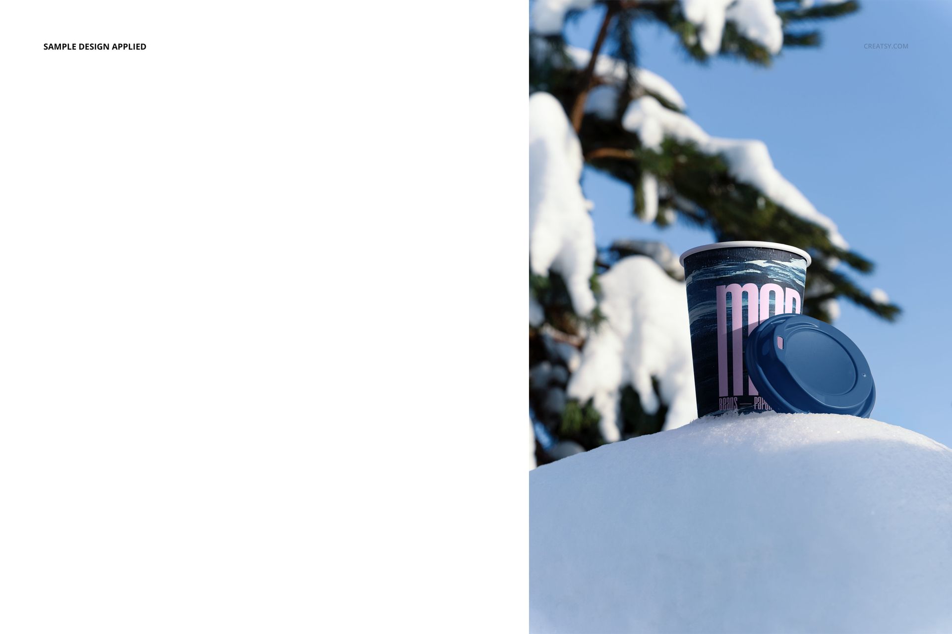 Winter paper cup mockup placed on a snowy surface outdoors, blue lid beside cup, pine tree in background.