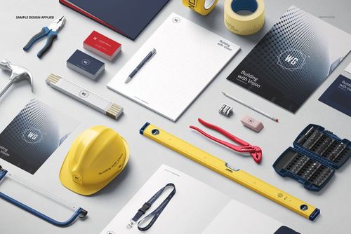 Construction company identity mockup set featuring stationery, business cards, tools, and a yellow hard hat on a light surface.