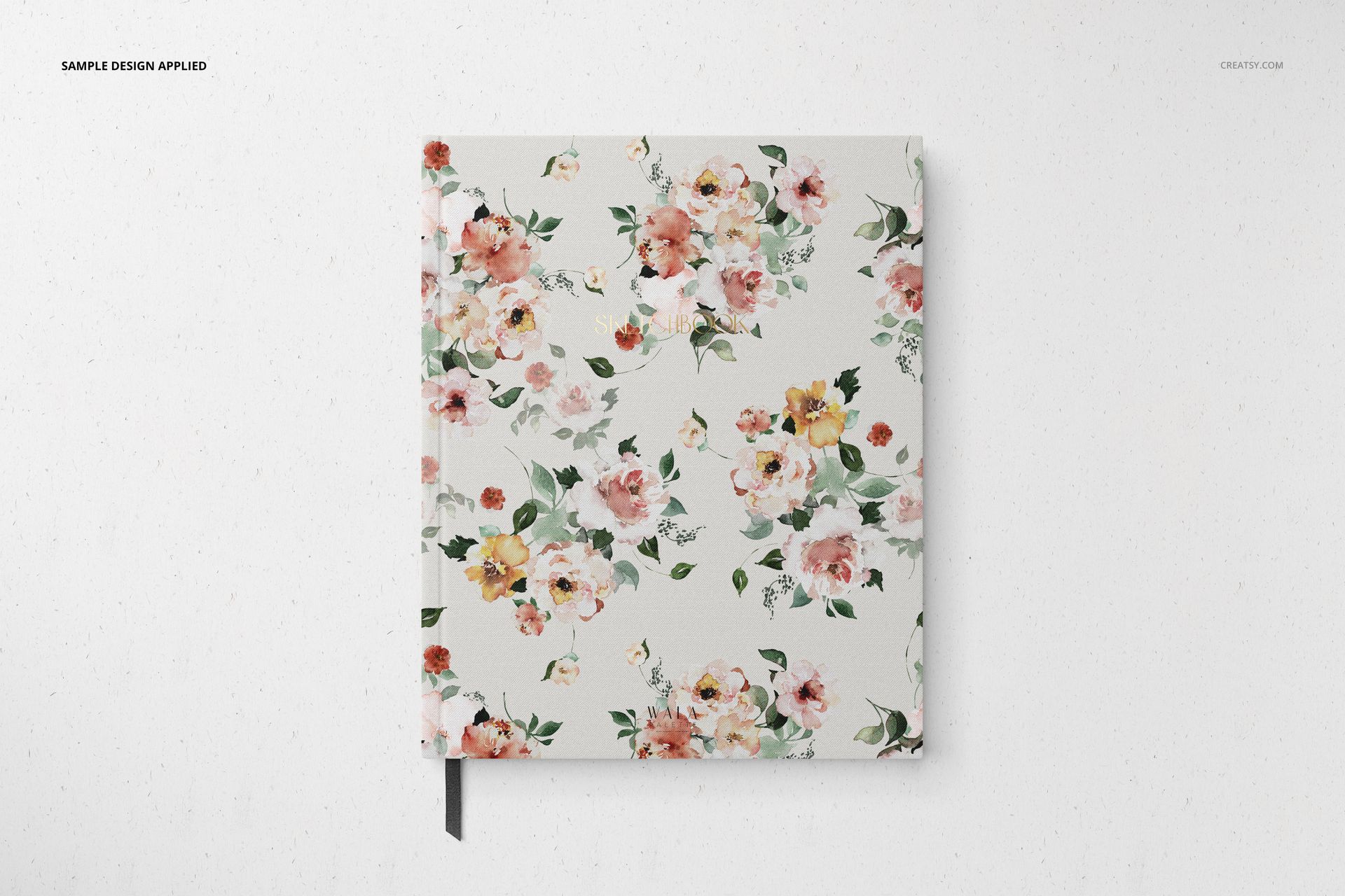 Stationery mockup featuring a closed notebook with a watercolor-style flower design, viewed from above on a white surface.