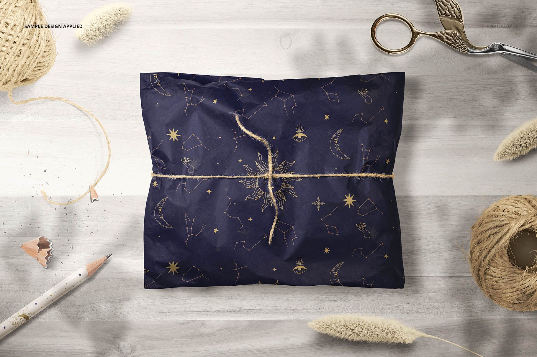 Gift wrapping tissue paper mockup featuring dark blue paper with gold celestial motifs, displayed from above on a table.