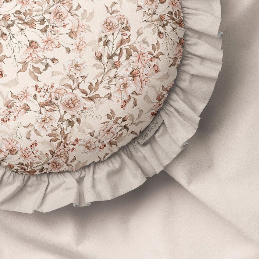 Round ruffled pillow mockup featuring a vintage floral pattern in soft pink and beige tones on a light fabric background.
