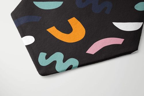 Close-up of a flannel dog scrunchie bandana mockup displaying multicolored curved shapes on dark fabric.