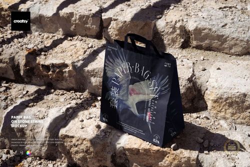 PSD mockup of a paper bag with decorative graphics and text displayed on rugged stone staircase outdoors.