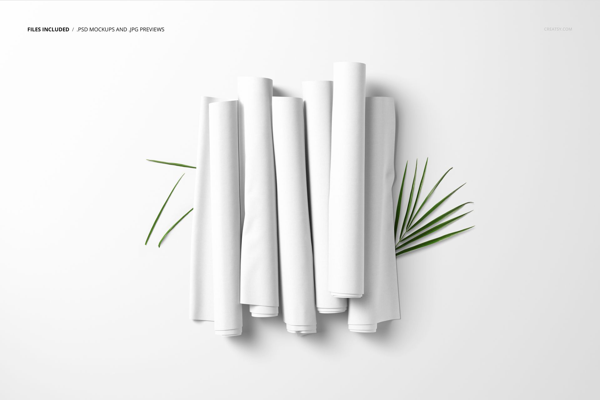 Multiple plain white fabric rolls displayed on a flat surface with two green palm leaves for decoration, PSD mockup style.