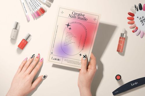 PSD mockup showing hands with decorative nails, a printed flyer, various nail polishes, and sample nail tips on a table.