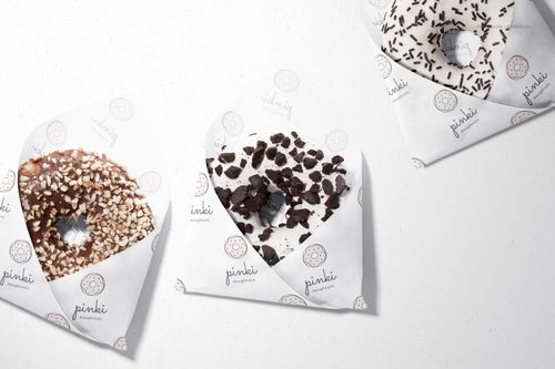 PSD mockup featuring three donuts in custom printed food safe paper, arranged on a clean, white tabletop.