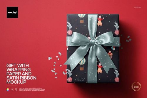 Top view of a mockup featuring a gift box with whimsical wrapping paper and a large satin bow on a red background.