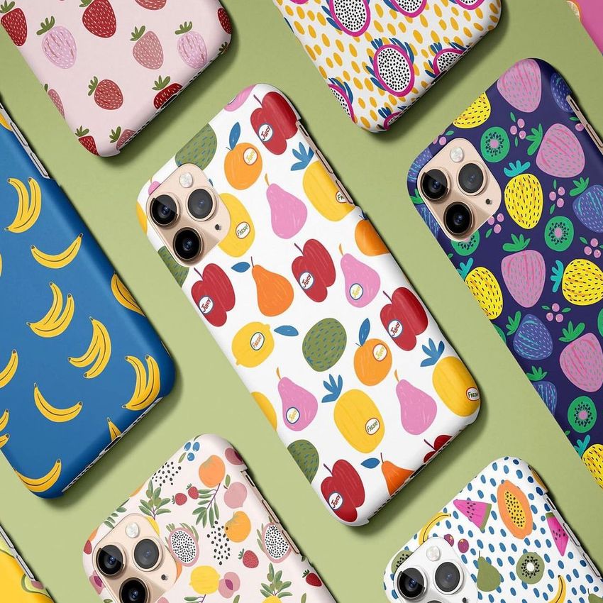 Top view of several iPhone 11 Pro matte snap cases arranged on a pastel green surface, each featuring colorful fruit patterns.