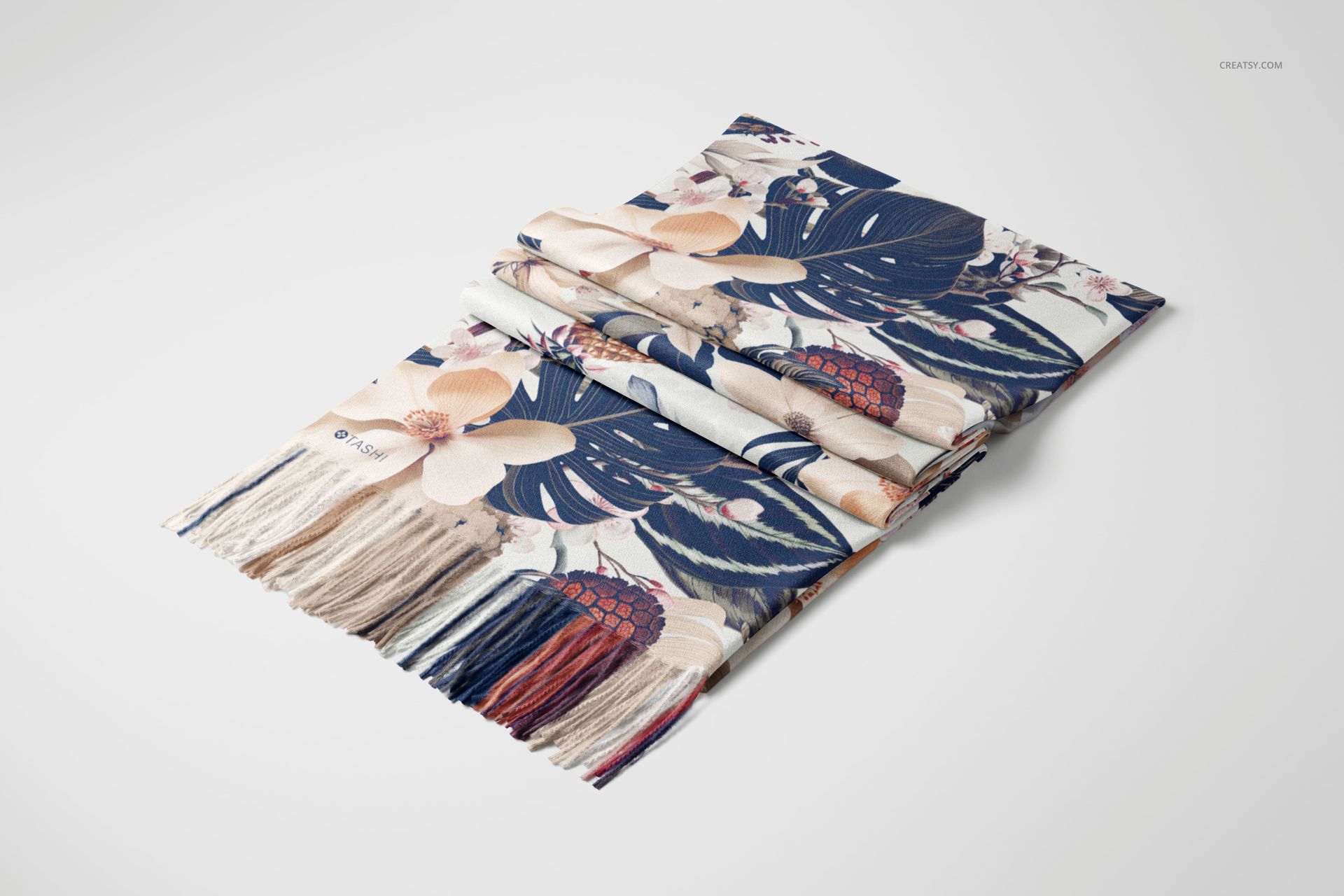Folded cashmere scarf with a floral and leaf pattern in navy, beige, and red, shown on a white surface.