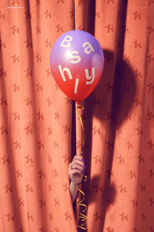 PSD mockup showing a single party balloon with lettering, held in front of an orange curtain with subtle patterns.