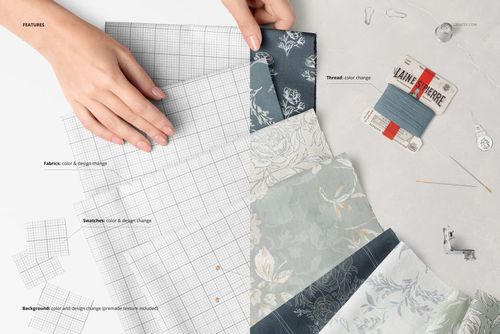 PSD mockup showing multiple patterned cotton fabric swatches, sewing tools, and a hand adjusting the materials on a white surface.