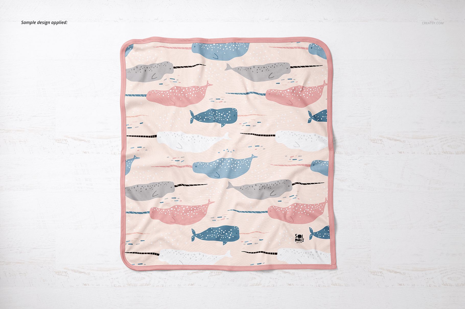 Square cotton baby blanket mockup featuring illustrated whales in soft colors, shown from a top-down perspective.