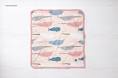 Square cotton baby blanket mockup featuring illustrated whales in soft colors, shown from a top-down perspective.