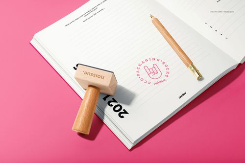 Stationery scene featuring a wooden stamp, open notebook, and gold pen on a bright pink surface, PSD mockup style.