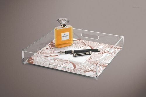Transparent lucite tray mockup with handles, displaying a leaf design insert, shown with perfume and pens on top.