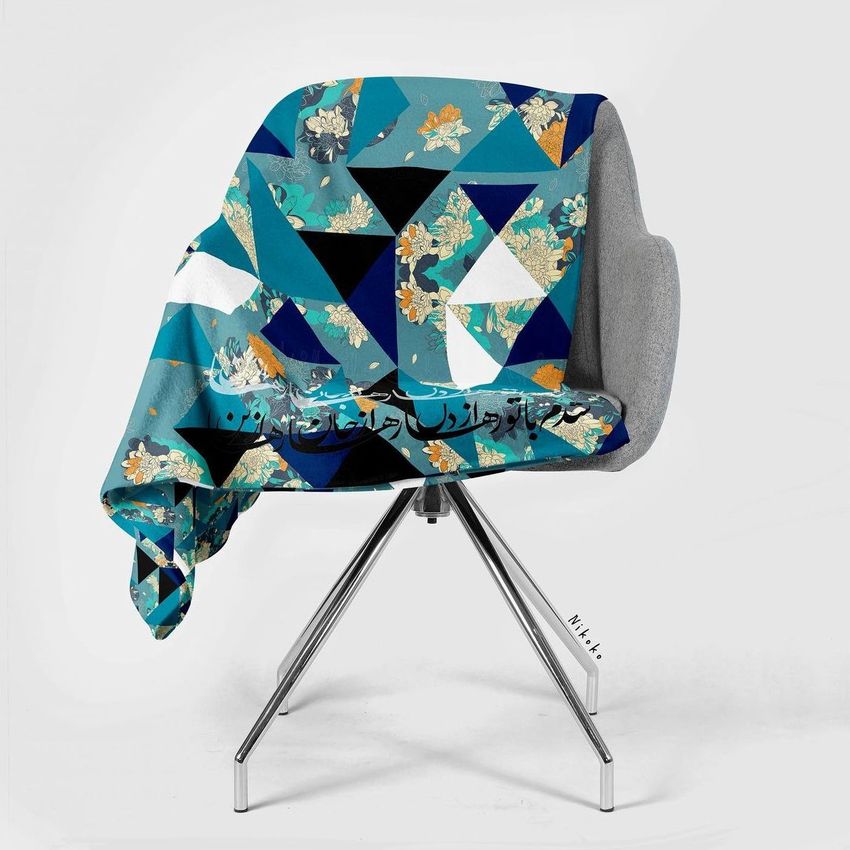Sherpa blanket mockup draped over a modern gray chair, featuring a geometric and floral pattern in teal, black, and gold tones.