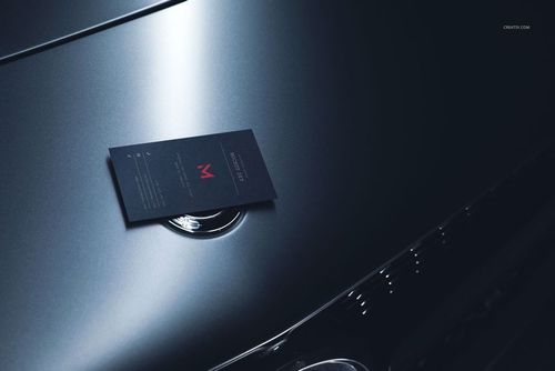 Automotive-themed business card mockup featuring a dark card resting on a glossy car hood, side perspective.