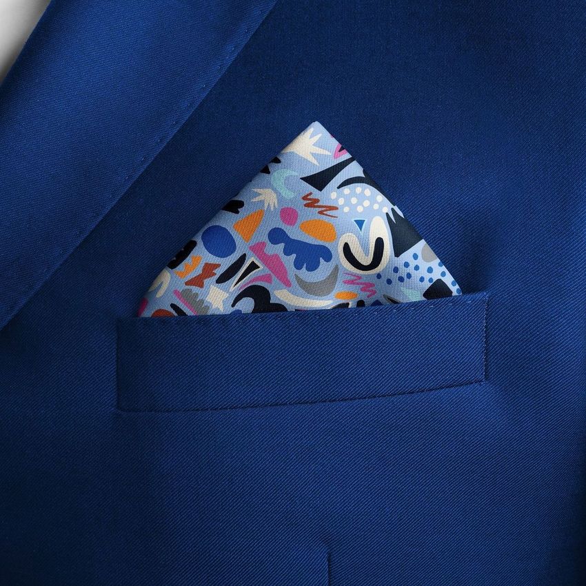 Pocket square mockup featuring a colorful abstract patterned fabric tucked into the chest pocket of a blue suit jacket.