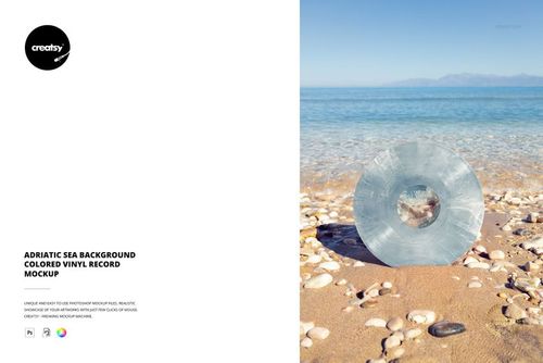 Transparent blue vinyl record mockup standing on a sandy beach, clear sea waves and distant mountains visible behind.