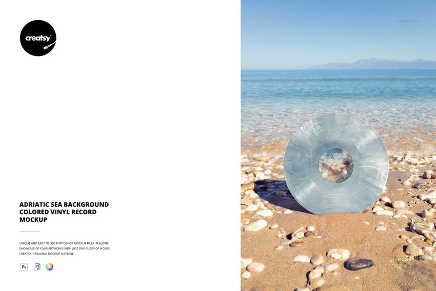 Transparent blue vinyl record mockup standing on a sandy beach, clear sea waves and distant mountains visible behind.