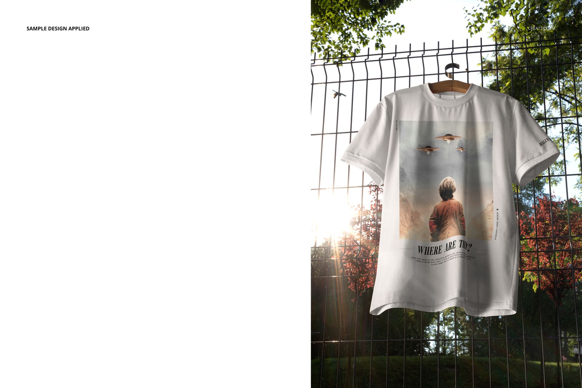 Front view of an oversized t-shirt mockup with a graphic design, displayed on a hanger against a wire fence and trees.