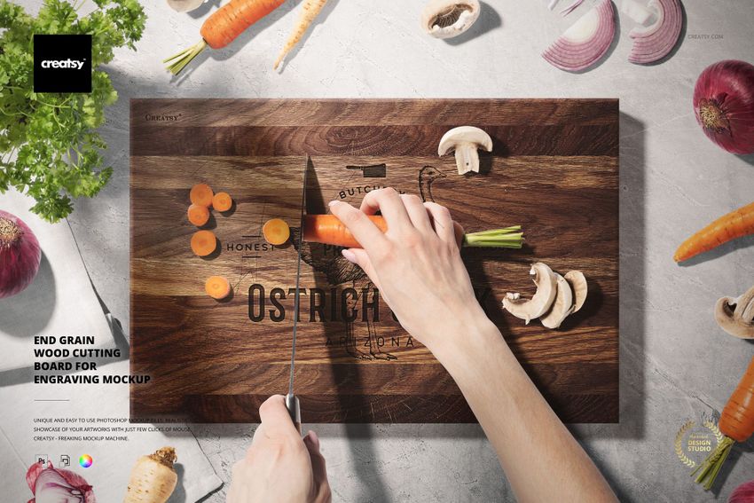End grain wood cutting board mockup with engraved design, surrounded by mushrooms, onions, and carrots being sliced.
