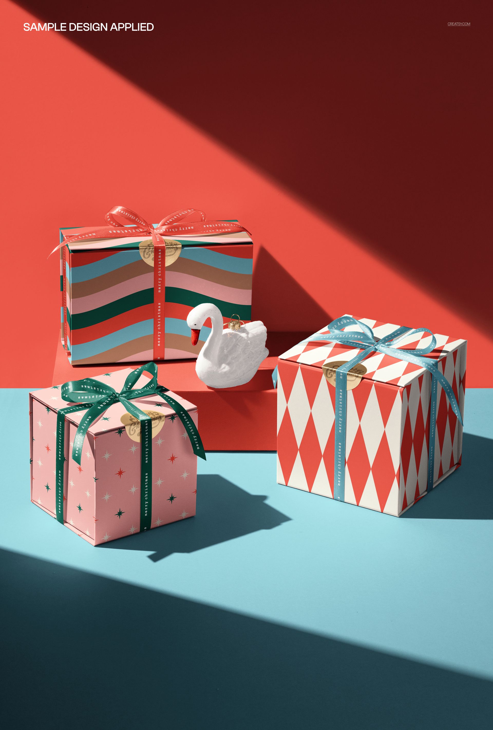PSD mockup showing three festive magnetic gift boxes with different designs, plus a white swan figurine as a prop.