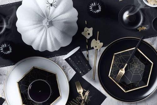 Halloween table setup mockup featuring black and white plates with spiderweb patterns, gold cutlery, and festive props.