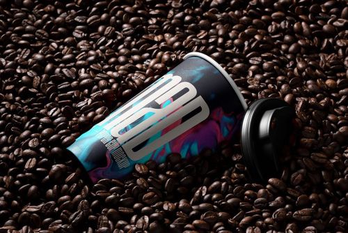 PSD mockup of a paper cup with a vibrant pattern surrounded by coffee beans, showing the cup at an angle.