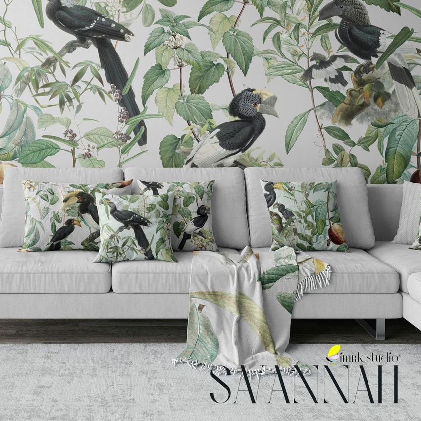 Modern living room sofa mockup with light gray upholstery, patterned pillows, and a botanical wallpaper featuring birds and leaves.