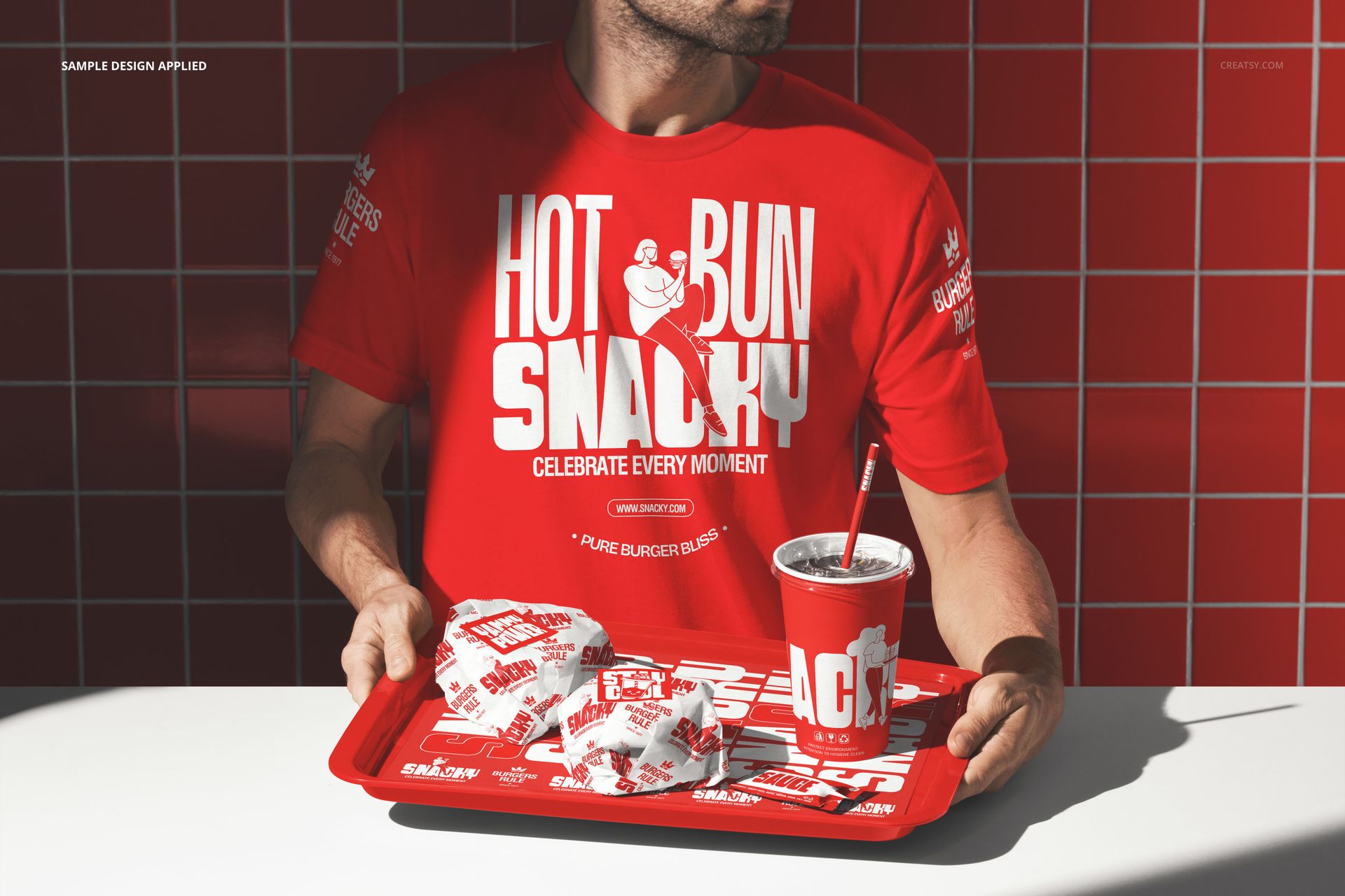 PSD mockup showing a man with a red tray containing burgers in branded wrappers and a drink, red tiled background.