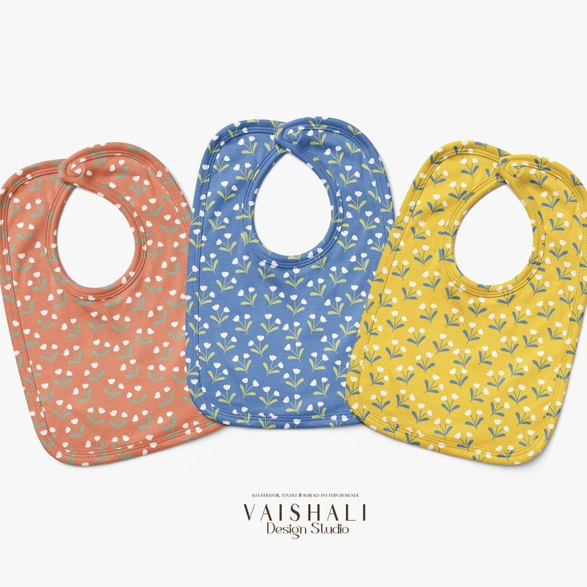 Three velcro fastening bibs mockup displayed side by side on a white background, featuring orange, blue, and yellow colors with small floral patterns.