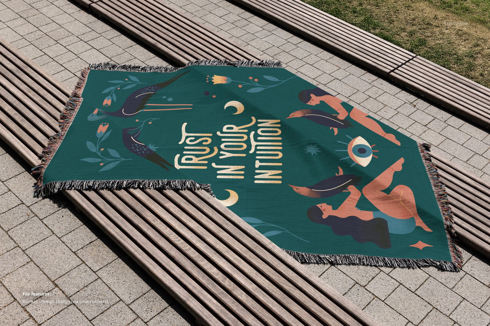 Mockup of a green woven throw blanket with fringe, featuring artistic designs and text, laid on outdoor benches.