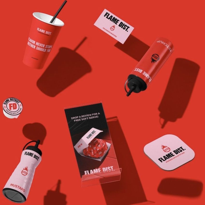 Floating fast food branding kit mockup featuring drink cups, condiment bottles, a coaster, and a folded flyer on a red background.