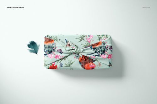 Furoshiki fabric wrap mockup featuring pastel blue textile with colorful roosters and flowers, viewed from above.