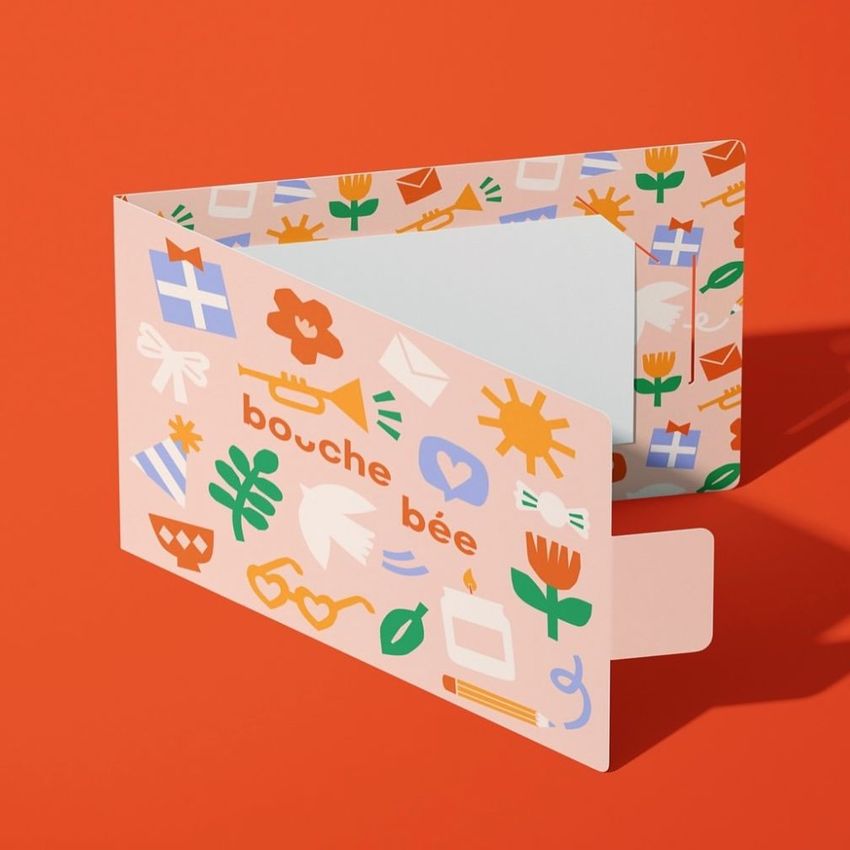 Gift card holder mockup displayed on a solid orange background, featuring colorful abstract illustrations and playful shapes.