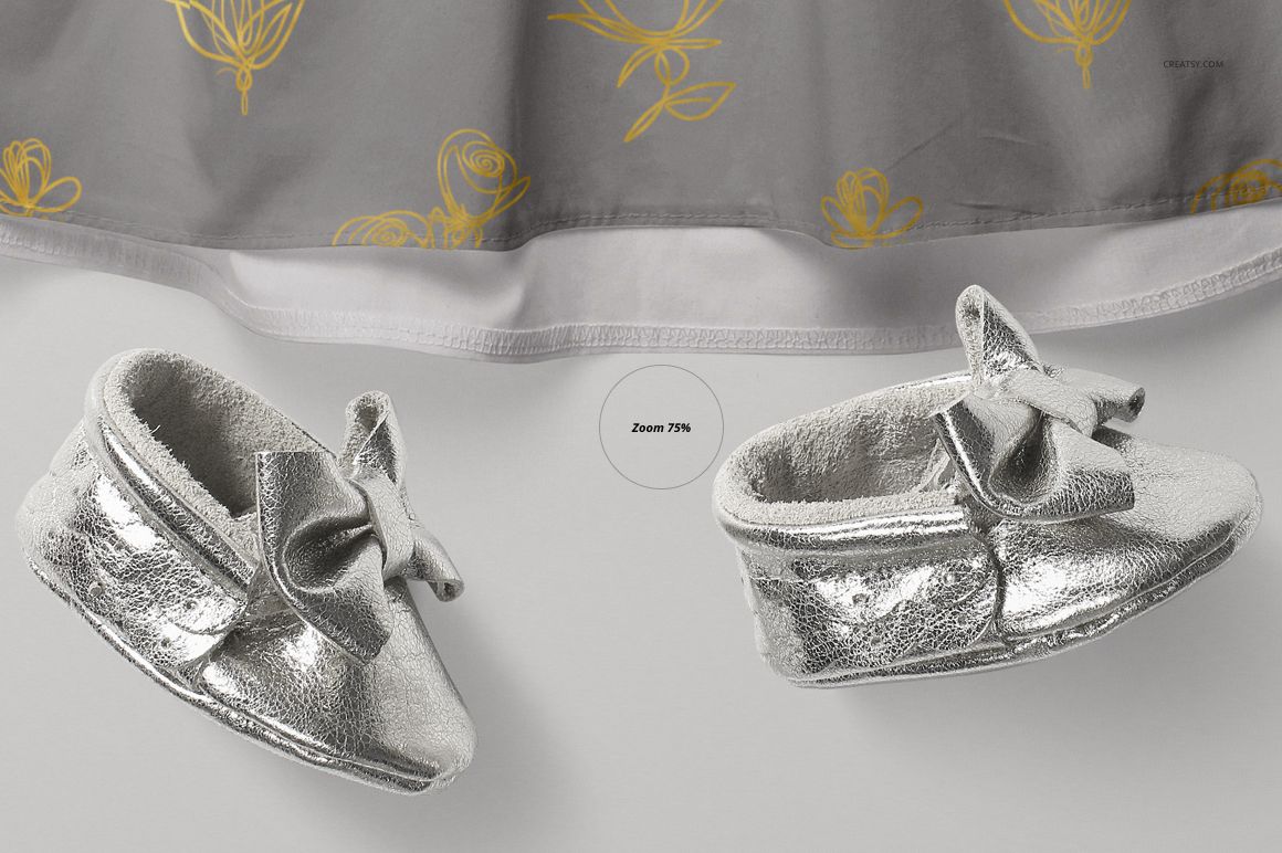 PSD mockup showing a gray baby dress with yellow floral accents and metallic silver baby shoes with decorative bows.