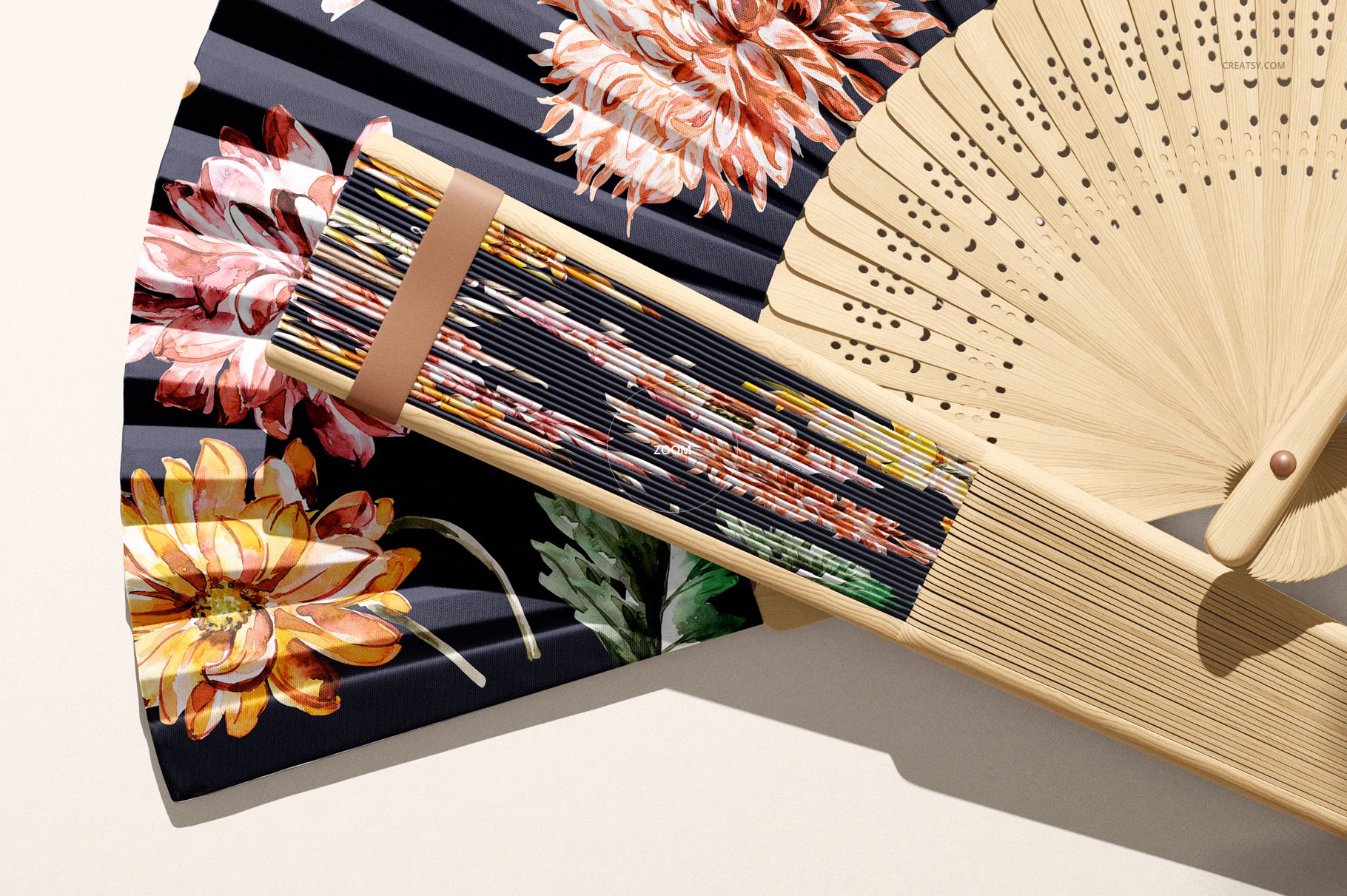 PSD mockup of a fabric hand fan featuring vibrant flower designs, displayed alongside a natural wood fan in close-up.