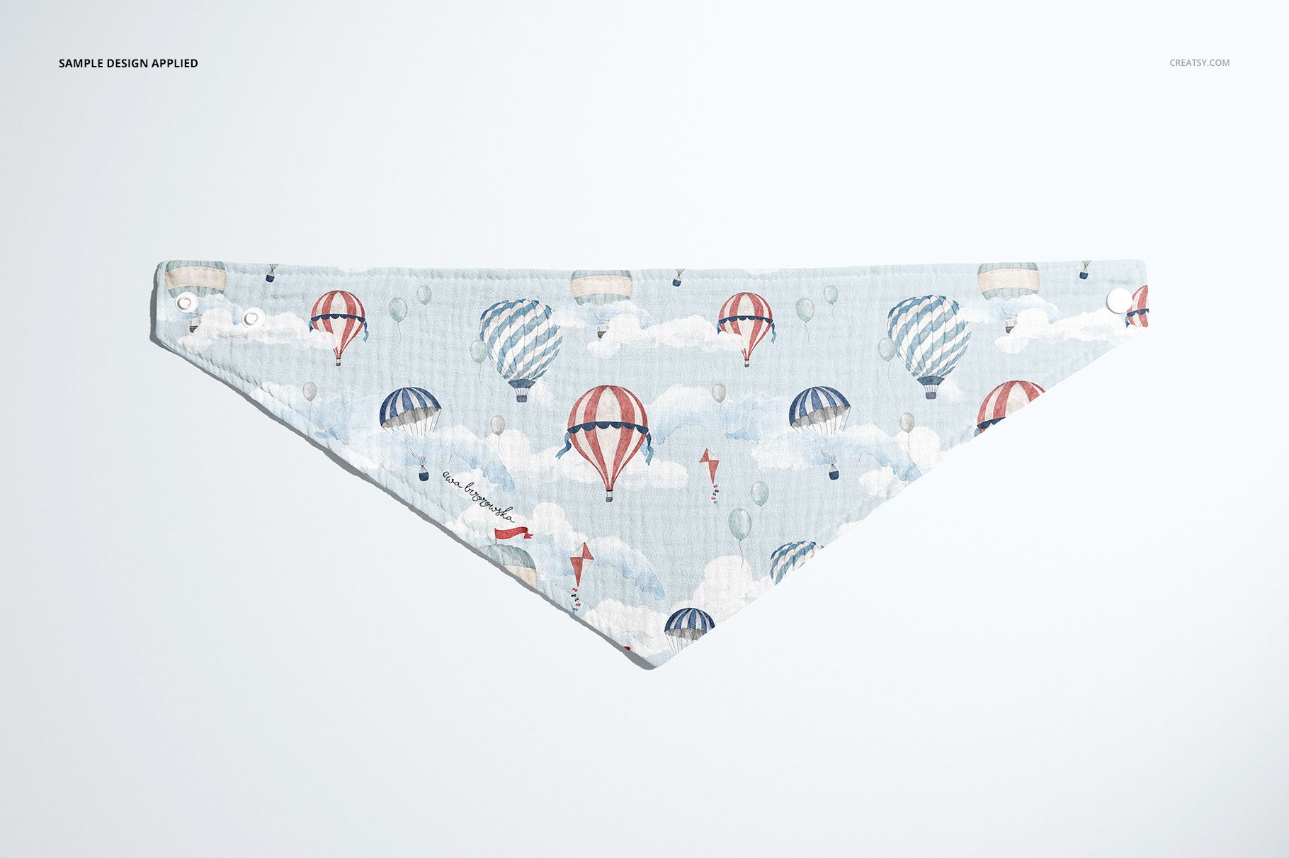 Triangular baby muslin bandana mockup featuring pastel hot air balloons and clouds, shown from above on a plain surface.