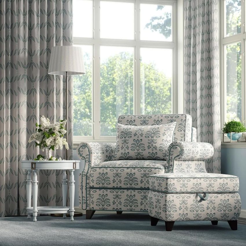 Victorian style armchair and ottoman mockup in a bright living room with patterned upholstery, near a window with leafy curtains.