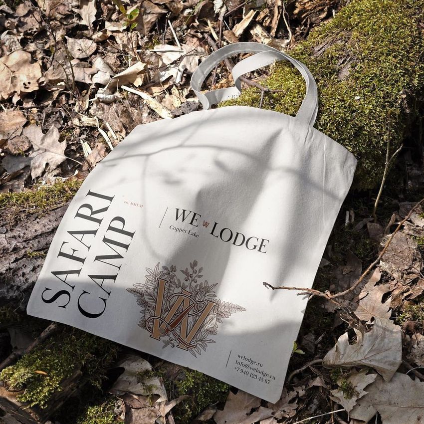 Tote bag mockup featuring a light fabric bag with bold text and decorative design, placed outdoors on mossy ground with dry leaves.