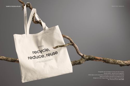 Front view of a cream-colored tote bag mockup with black text, hanging on a branch against a neutral background.