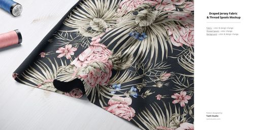 PSD mockup featuring draped jersey fabric with botanical design, accompanied by spools of thread on a light tabletop.