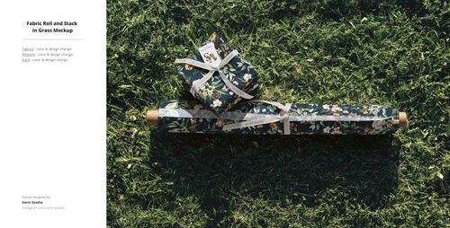 Outdoor PSD mockup showing a fabric roll and fabric stacks with botanical print placed on grassy ground.