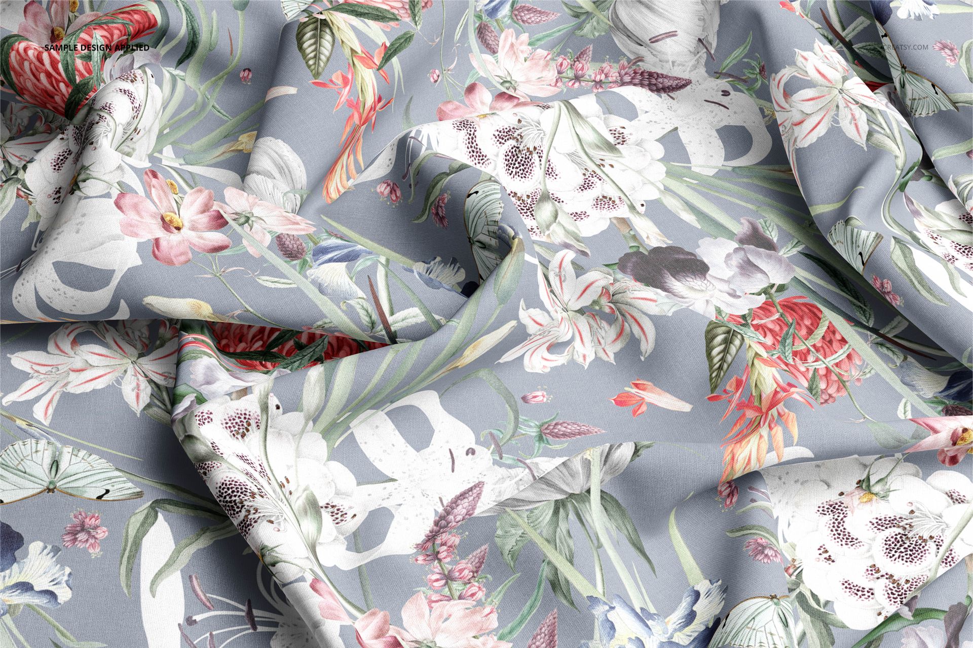Wrinkled cotton textile mockup displaying a colorful floral pattern on a muted blue base, viewed from above.
