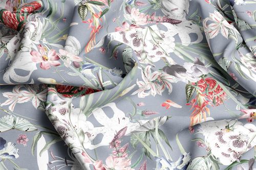 Wrinkled cotton textile mockup displaying a colorful floral pattern on a muted blue base, viewed from above.
