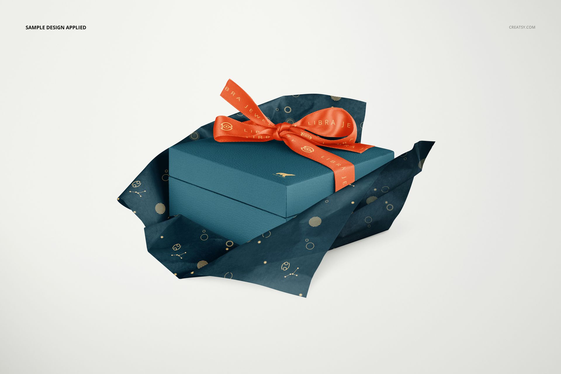 PSD mockup showing a jewelry box in blue, wrapped with dark tissue paper featuring gold dots and an orange bow.